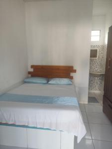 Schlafzimmer mit einem Bett mit einem Kopfteil aus Holz in der Unterkunft Hospedagens Icapui Mare Blu in Icapuí