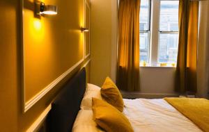 a bedroom with a bed with yellow pillows and a window at CAMPBELL 100 DUNFERMLINE in Fife