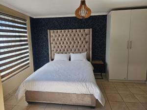 a bedroom with a large bed with a large headboard at YELLO GUEST HOUSE CE2 in Vanderbijlpark