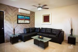 una sala de estar con un sofá de cuero negro y mesas. en Hotel Suites Paraíso, en Mérida