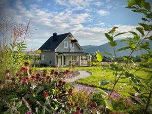 una casa con un jardín con flores en el primer plano en Osada Aurora Całoroczne domki z jacuzzi z widokiem na jezioro i góry, en Miszkowice