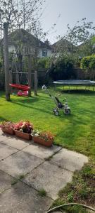 een tuin met twee planten en een schommel en een kinderwagen bij Brand New Extension Private Studio in Londen