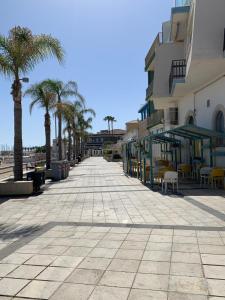 a sidewalk with palm trees and a building at Marina Design Apartment in Marina di Ragusa