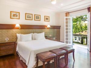 um quarto com uma grande cama branca e uma janela em Hotel Fazenda Dona Carolina em Itatiba