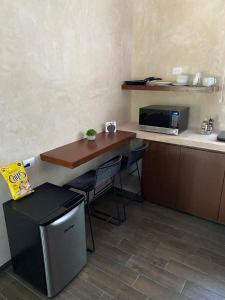 a small kitchen with a table and a microwave at Hotelito YUM KAAX in Mérida