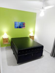 a bed in a room with a green wall at Ap frente para o mar in Caraguatatuba