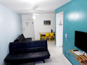 a living room with a black leather couch and a table at Ap frente para o mar in Caraguatatuba