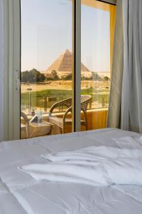 1 dormitorio con cama y vistas a una pirámide en Pyramids Land Hotel en El Cairo