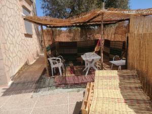 een pergola met een tafel en een tafel en stoelen bij استمتع بالإقامة في فيلا أحلامك in El Khemis des Meskala