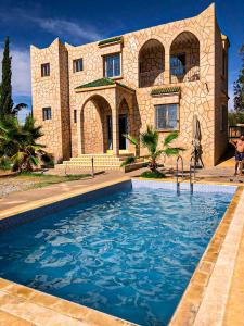 a house with a swimming pool in front of a house at استمتع بالإقامة في فيلا أحلامك in El Khemis des Meskala