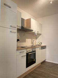 een keuken met witte kasten en een fornuis met oven bij Im Zentrum, Modernes City Apartment in Würzburg