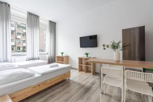 a white bedroom with a bed and a table at T&K Apartments - 2 Room Apartment - Ground Floor in Düsseldorf