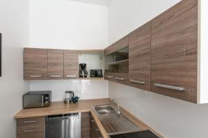 T&K Apartments - 2 Room Apartment - Ground Floor في دوسلدورف: مطبخ بدولاب خشبي ومغسلة