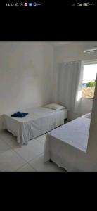 two beds in a white room with a window at DUPLEX 5 ESTRELAS A 100 METROS DA PRAIA in Porto Seguro