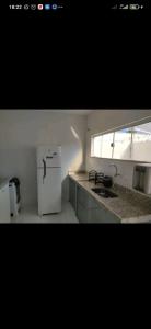 a kitchen with a white refrigerator and a sink at DUPLEX 5 ESTRELAS A 100 METROS DA PRAIA in Porto Seguro