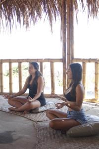 Dos mujeres sentadas en el suelo en meditación en 9 Lunas, en Zorritos