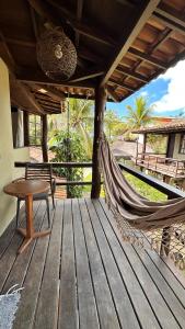 a hammock on a deck with a table and a bench at Pousada Villa Zena - Pé na areia in Arraial d'Ajuda