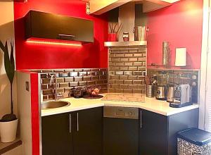 una pequeña cocina con fregadero y paredes rojas en Modern apartment , Golfe de Saint Tropez, en Cogolin