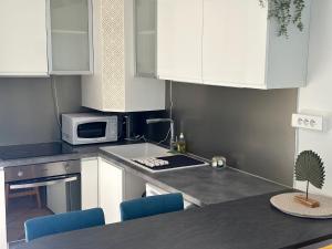 uma cozinha com armários brancos, um micro-ondas e uma mesa em Le cosy cottage d'Alex em Ardon