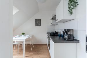 eine weiße Küche mit einem weißen Tisch und Stühlen in der Unterkunft T&K Apartments - Apartments 20 Min to MESSE DUS in Krefeld