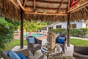 a patio with chairs and a table and a pool at Solar Heated Pool Spa Tiki Hut Huge Backyard Hammock Retro Bikes in Pompano Beach