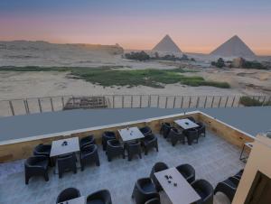 un restaurante con mesas y sillas y vistas a las pirámides. en Pyramids Land Hotel en El Cairo