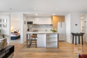 uma cozinha e sala de estar com um balcão e uma mesa em Experience Port Melbourne on Delightful Dow Street em Melbourne