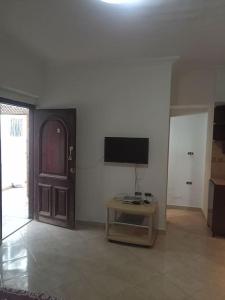 uma sala de estar com uma televisão, uma mesa e uma porta em An amazing studio at AlHadaba em Sharm el Sheikh