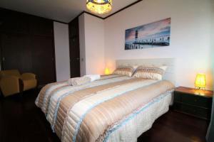 a bedroom with a large bed and a chandelier at Apartamento Figueira da Foz - Praia do Relógio in Figueira da Foz