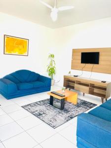 ein Wohnzimmer mit 2 blauen Sofas und einem TV in der Unterkunft Carvalho de Paquetá in Rio de Janeiro