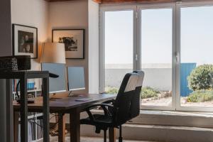 an office with a desk and a chair and windows at Villa Tamar - Azenhas do Mar in Azenhas do Mar