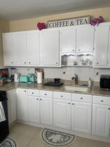 a kitchen with white cabinets and a coffee and tea sign at Queens chateau in Laurelton