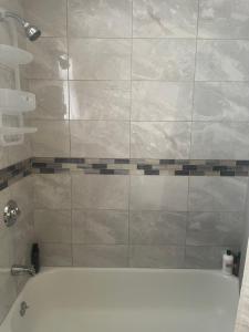 a bathroom with a tub and a tiled shower at Queens chateau in Laurelton