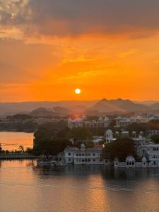 a sunset over a city on the water at Tamasha Udaipur in Udaipur