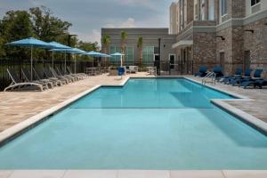 una piscina en un hotel con sillas y sombrillas en Hilton Garden Inn Pensacola Downtown en Pensacola