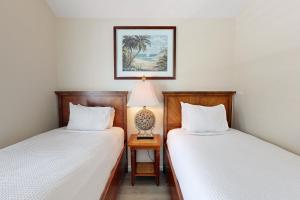 a bedroom with two beds and a table with a lamp at Reef House in Duck Key