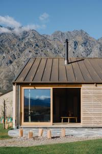 a house with a roof with mountains in the background at The Earth House @ Jacks Point in Frankton Wharf