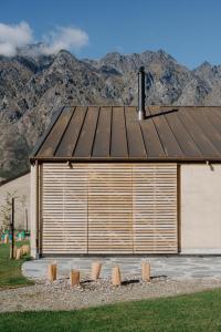 a large wooden building with mountains in the background at The Earth House @ Jacks Point in Frankton