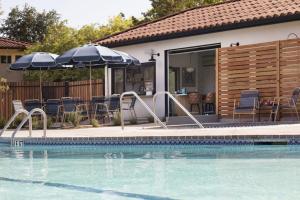ein Pool mit Sonnenschirmen und Stühlen sowie ein Haus in der Unterkunft Sandman Hotel in Santa Rosa