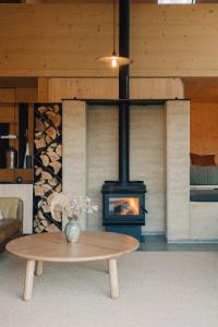 a fireplace in a living room with a table and a stove at Jacks Point - Earth House in Frankton Wharf