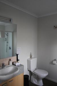 y baño con aseo, lavabo y espejo. en ASURE Kaimai View Motel, en Katikati