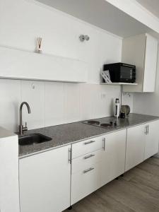 a white kitchen with a sink and a microwave at 57 entre 24 y 25, La Plata - Alquiler temporario in La Plata