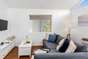 a living room with a gray couch and a window at Rothery Escape - A Cosy Coastal Cottage in Bellambi