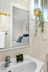 y baño con lavabo blanco y espejo. en Rothery Escape - A Cosy Coastal Cottage en Bellambi