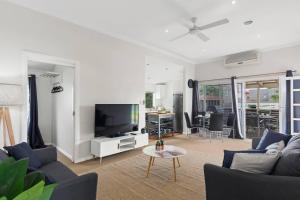 a living room with a couch and a tv at Saltwater Escape - Live the Sand and Surf Lifestyle in Thirroul