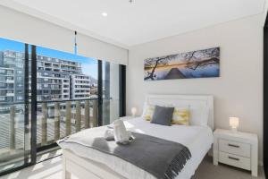um quarto com uma cama branca e uma varanda em 'Wollongong Inner-city Escape' Bright Urban Oasis em Wollongong