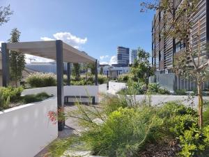 臥龍崗的住宿－'Wollongong Inner-city Escape' Bright Urban Oasis，一个带凉棚和长凳的花园