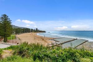 a beach with a volleyball court and the ocean at Saltwater Escape - Live the Sand and Surf Lifestyle in Thirroul