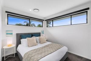 East Corrimal Escape - Beautiful Beachside Living في ولونغونغ: غرفة نوم بها سرير ونافذتين