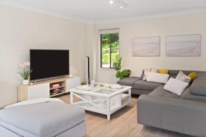 a living room with a couch and a tv at 'Garden Escape' Serene Coastal Living in Wollongong 